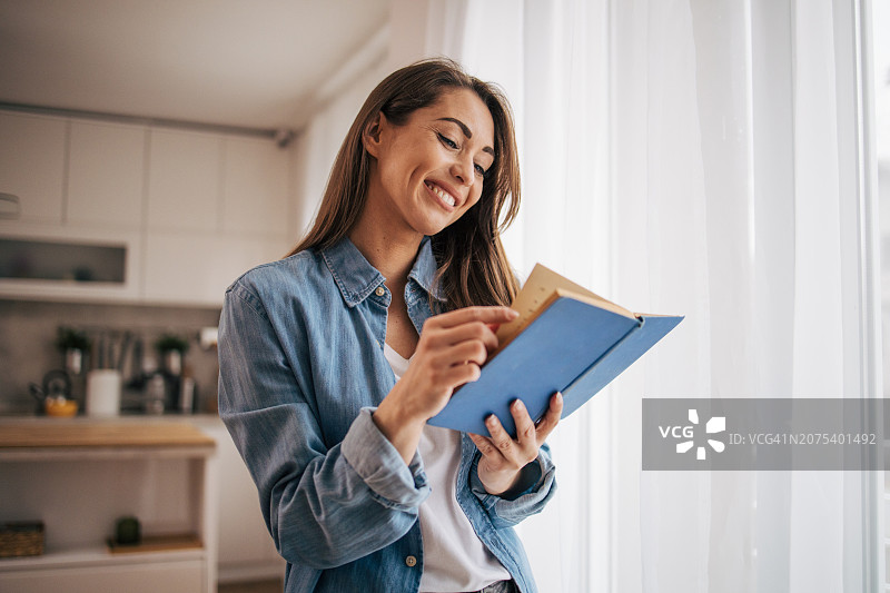 女人在客厅窗边读书，享受美好的一天图片素材