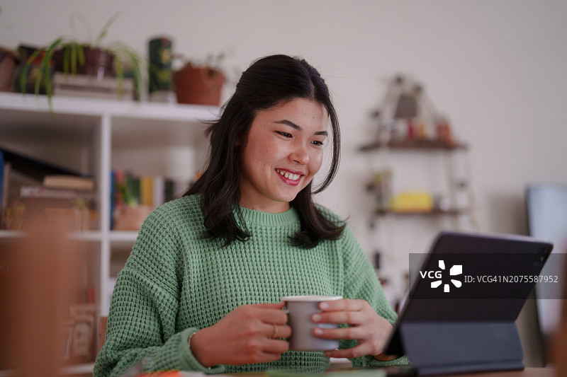 千禧一代亚洲女人在家用数位板办公图片素材