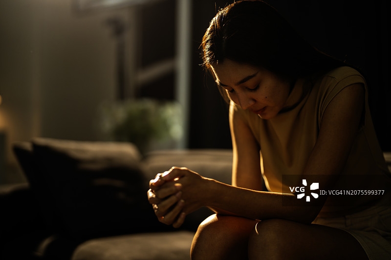 情绪低落的女人坐在黑暗的卧室里图片素材