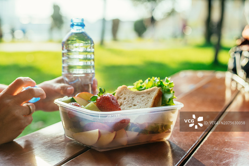 女人在公园的桌子上享用午餐图片素材