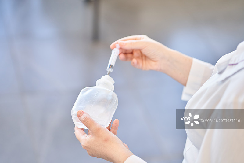身穿白大褂的护士拿着注射器和生理盐水图片素材