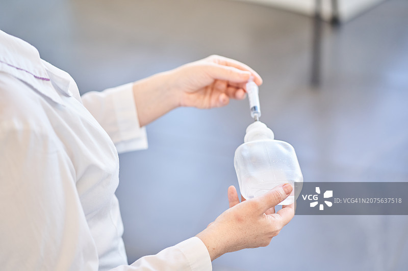 身穿白大褂的护士拿着注射器和生理盐水图片素材