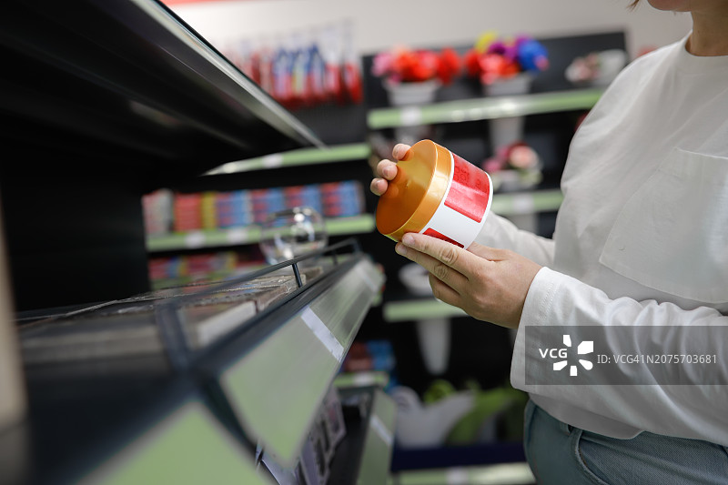 在商店货架附近检查发膜和润肤霜罐子的大码匿名女性图片素材