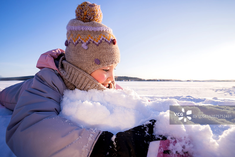 一个穿着冬装的女孩拥抱着白色的蓬松雪图片素材