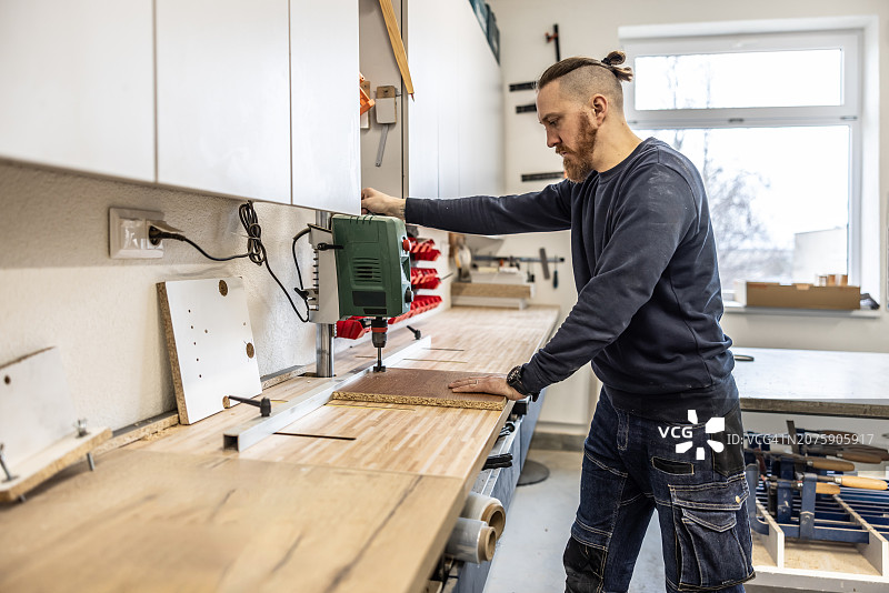 木匠在木工车间的木板上钻孔图片素材