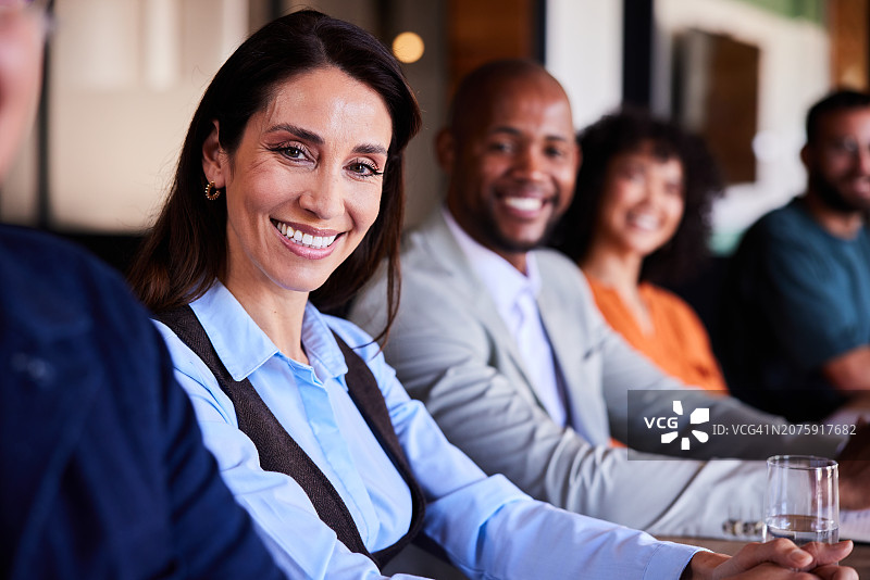 面带微笑的商业女性和一群不同的同事坐在会议室里图片素材