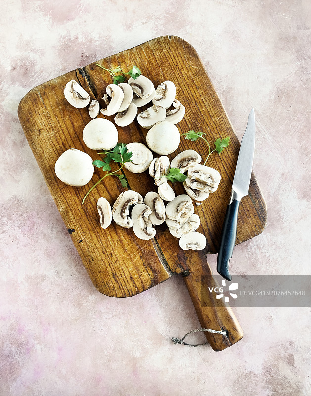 粉色风化背景木制砧板上的白色蘑菇图片素材