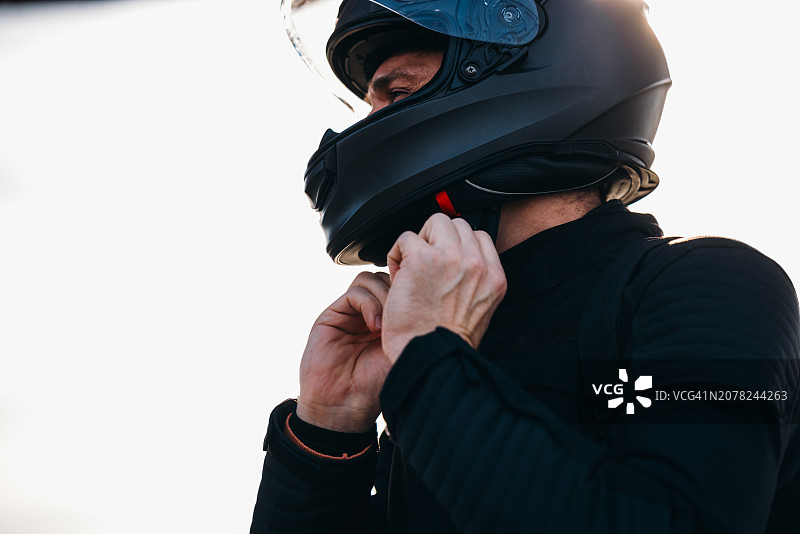 匿名摩托车手戴上头盔，准备骑行图片素材