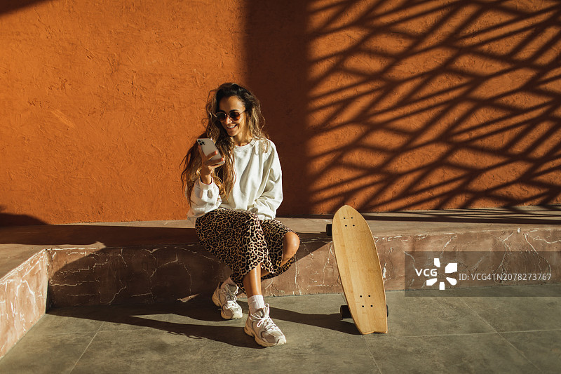 时髦的潮女玩滑板后在社交媒体上消磨时光图片素材