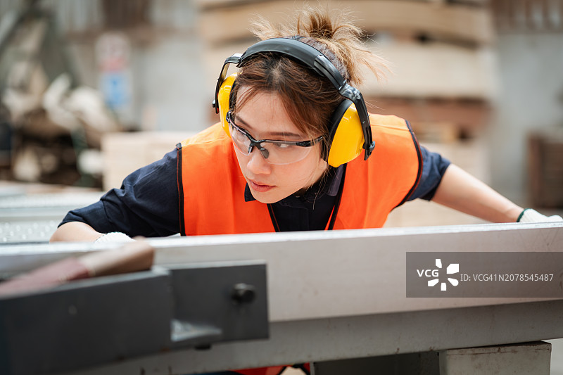 托盘厂的女工将木材装入机器进行切割图片素材