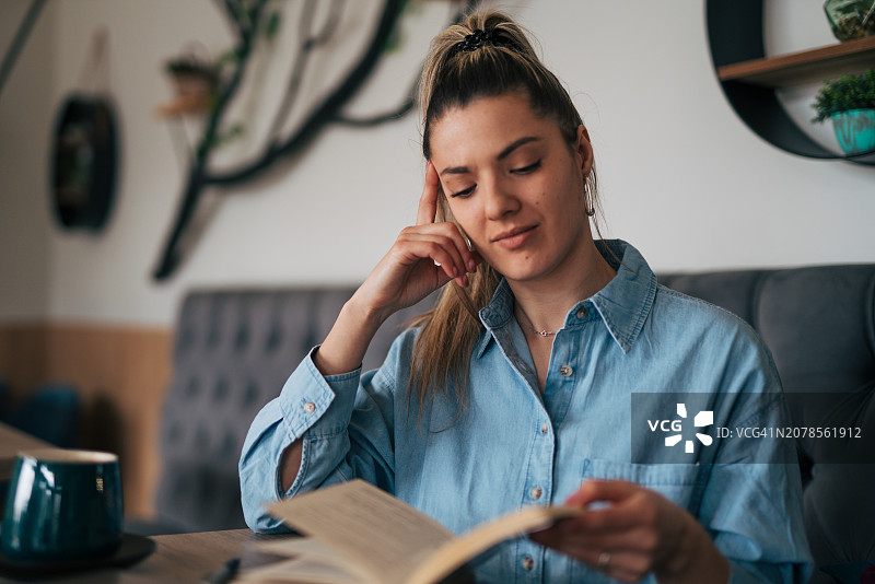 年轻女人在咖啡馆看书图片素材
