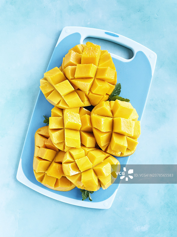 蓝色背景下砧板上的芒果切片图片素材