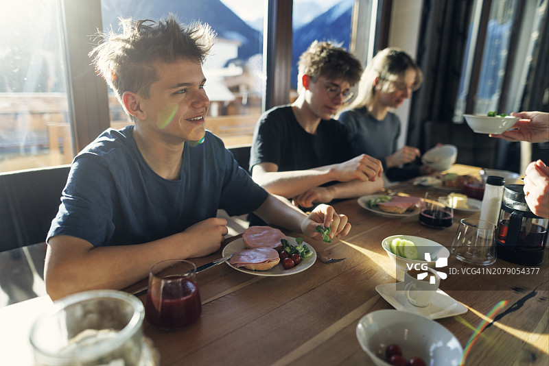 一家人一起享用早餐——面包、奶酪、茶和蔬菜图片素材