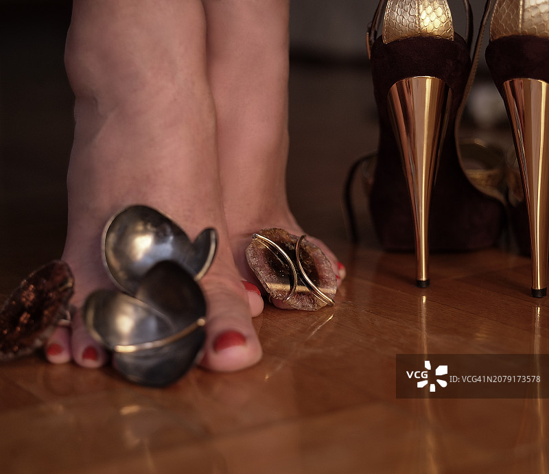 女性穿着高跟鞋站在地板上的腿部特写图片素材
