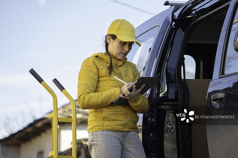 女快递员检查待交付的邮政包裹图片素材