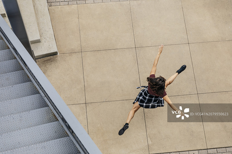 女人在人行道楼梯附近跳跃（高角度全身照）图片素材