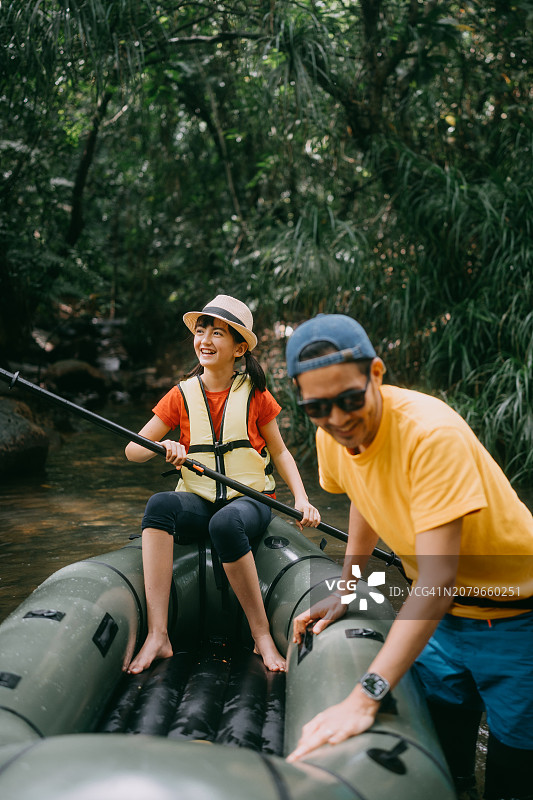 父亲在雨林中拉着皮划艇，女儿同在图片素材