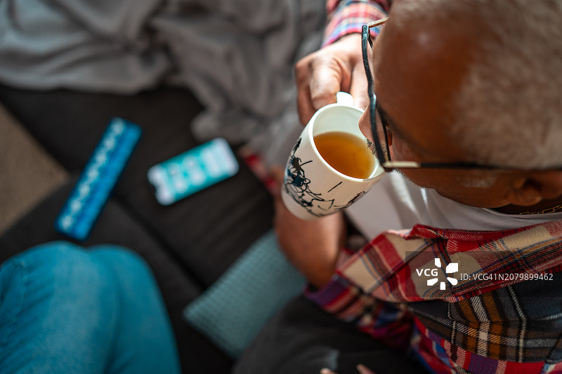 生病在家，拿着茶杯的老年男性图片素材