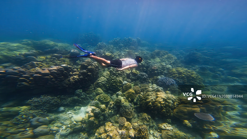 男人戴着呼吸管面罩和脚蹼在水下快乐地观赏珊瑚礁图片素材