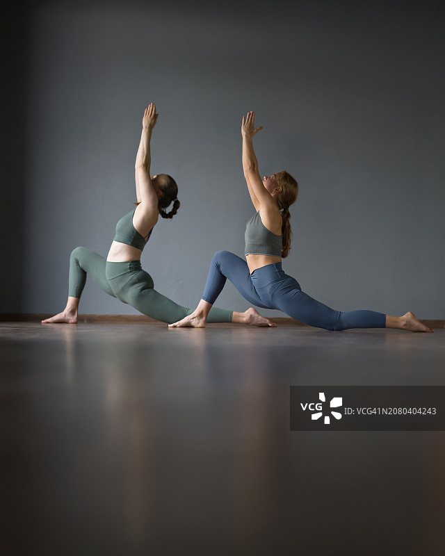 两名女子在健身房做瑜伽，骑马式，健身拉伸腿部肌肉图片素材