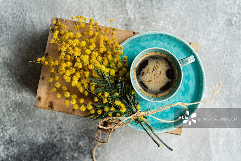 俯视视角：桌子上的一杯黑咖啡和一束黄色含羞草图片素材