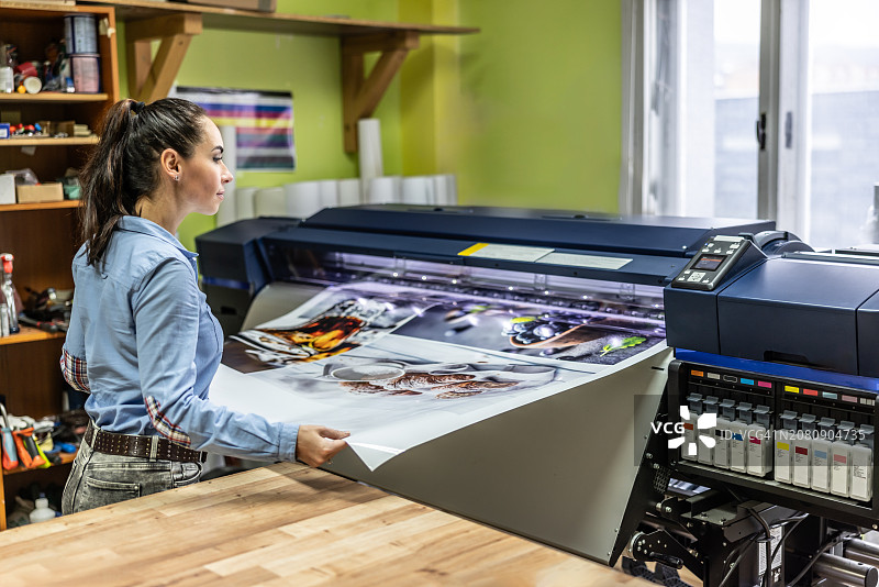 一名女工在手动检查CMYK胶印机的质量图片素材
