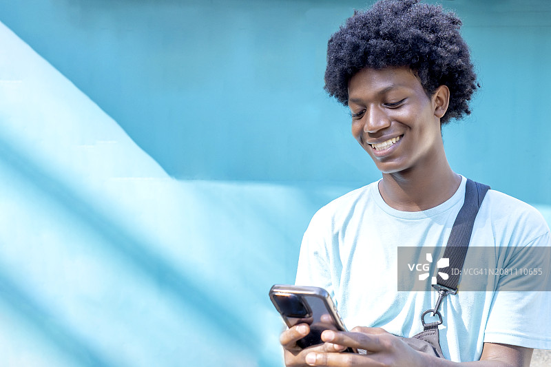使用手机微笑的年轻哥斯达黎加男子图片素材