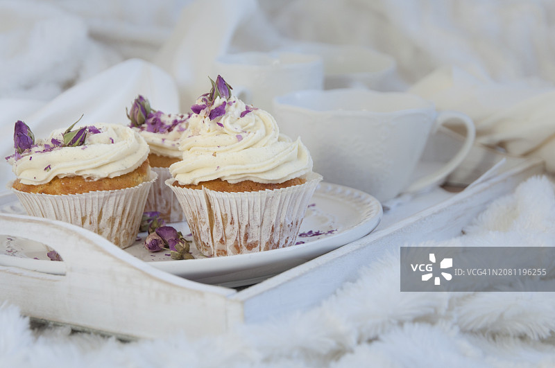 白色托盘上的干玫瑰花瓣香草纸杯蛋糕图片素材