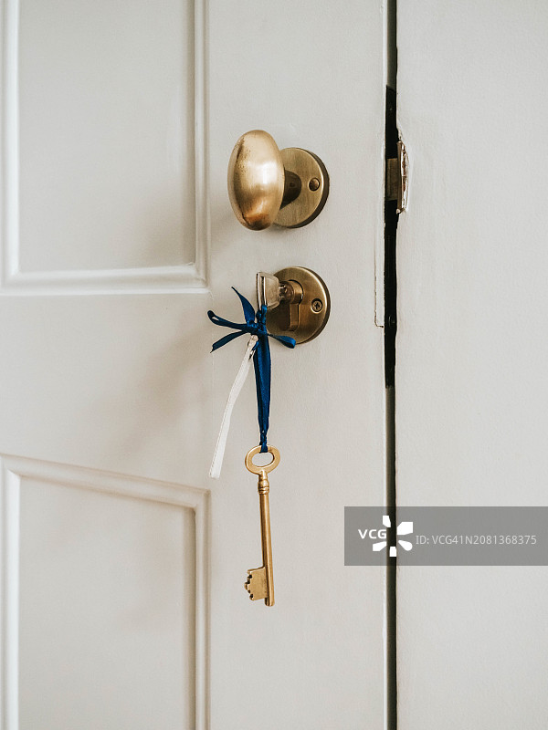 挂在黄铜门把手上的复古钥匙，象征安全和家图片素材