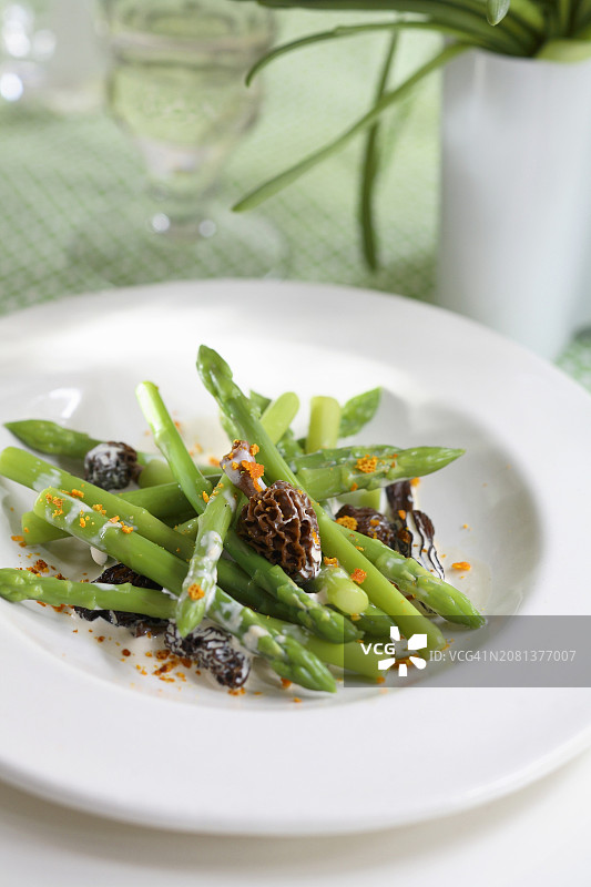 奶油酱汁中的绿色芦笋配羊肚菌和切碎的橙皮图片素材