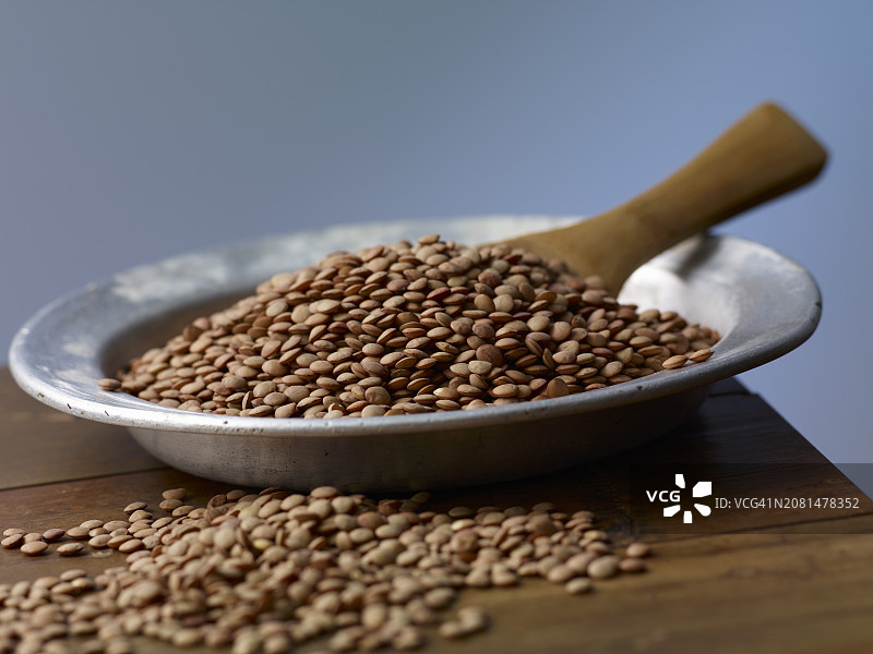 木桌金属盘上的棕色小扁豆图片素材