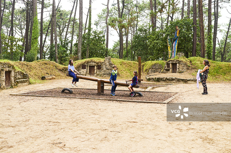 孩子们在格罗比茨村玩跷跷板，母亲在一旁观看图片素材