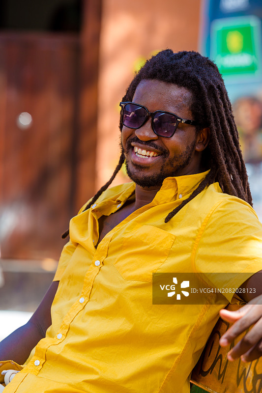 坐在公园长椅上微笑的时尚男人图片素材