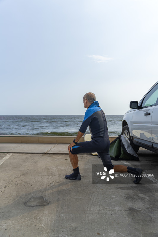 年长的冲浪者做伸展运动准备下海图片素材
