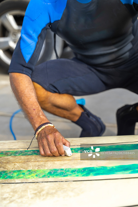 冲浪者为冲浪板打蜡准备下海图片素材