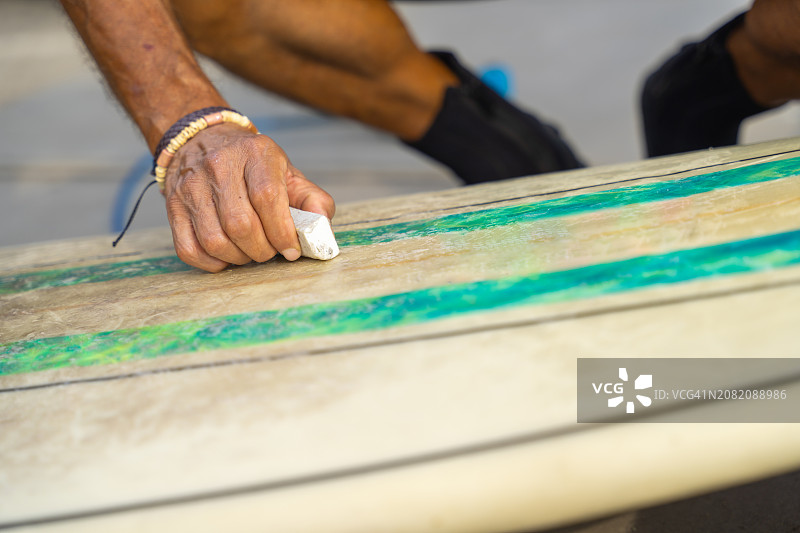 成年冲浪者给冲浪板打蜡准备下海图片素材