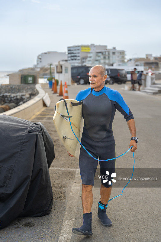 成年冲浪者沿着木板路携带冲浪板图片素材