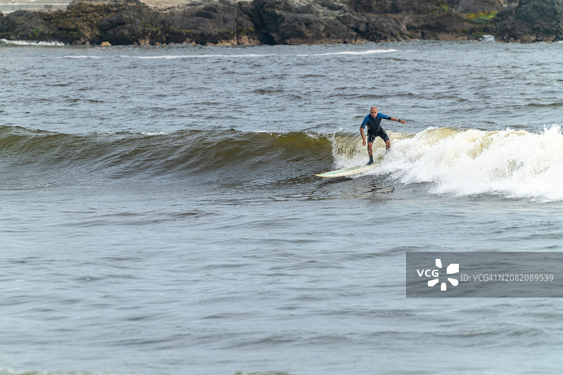 年长的冲浪者在海中冲浪图片素材