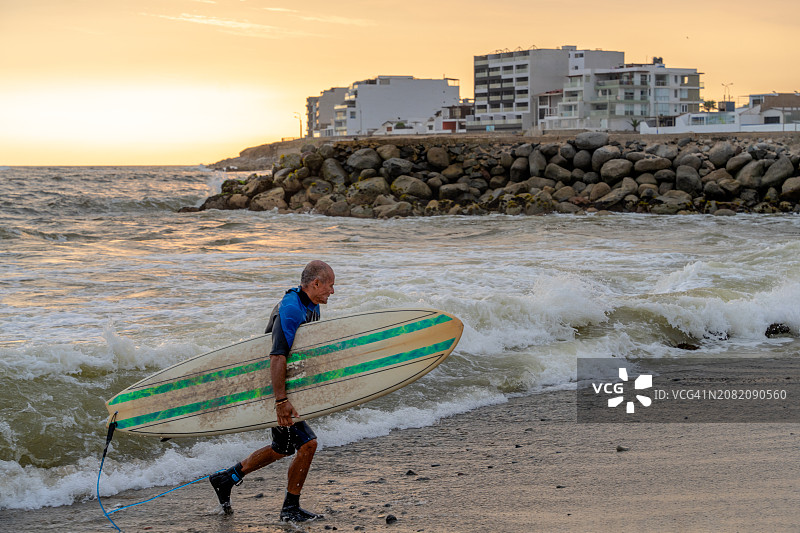 成年男子抱着冲浪板从海里出来图片素材