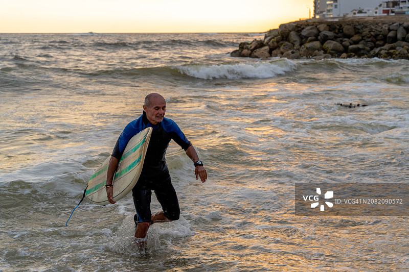 日落时分冲浪后上岸的中年人图片素材