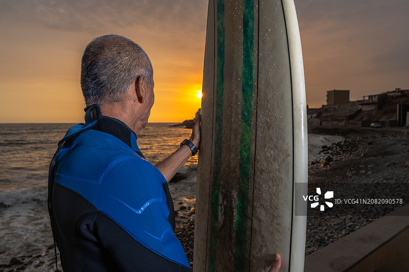 年长的男人冲浪后看着日落图片素材