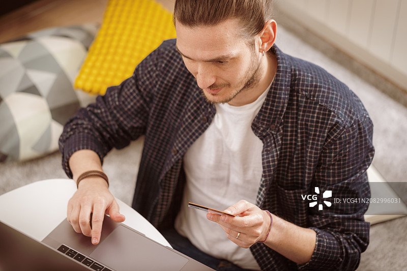 年轻男人在家线上用信用卡支付图片素材