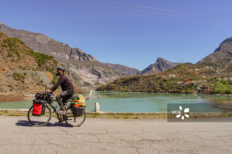 骑行冒险：中年自行车手在壮丽山脉和宁静湖泊中的旅程图片素材