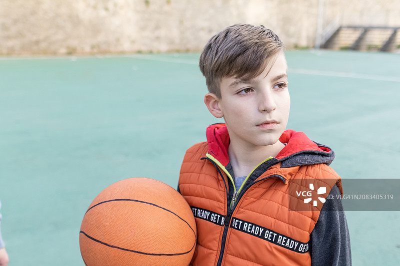 男孩在运动场上抱着篮球图片素材