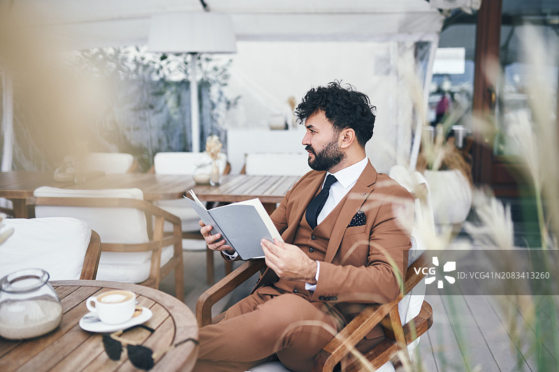 精致的放松：有品位的男人在高级咖啡馆放松身心，附菜单图片素材