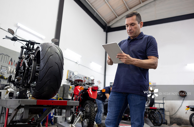修理工在修理店使用平板电脑修理摩托车图片素材