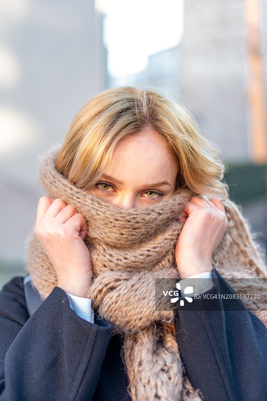 用围巾遮住脸的金发女人图片素材