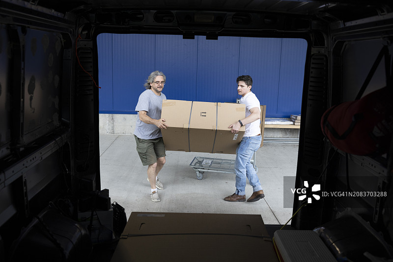 货物箱转移：两名男人将箱子从仓库运输到货车图片素材