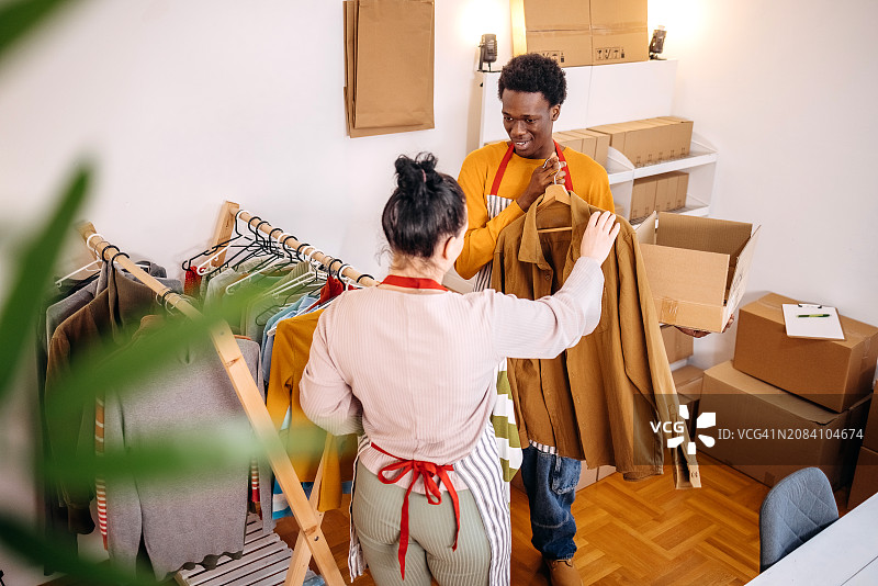 挑选衣服以完成客户订单的年轻人图片素材