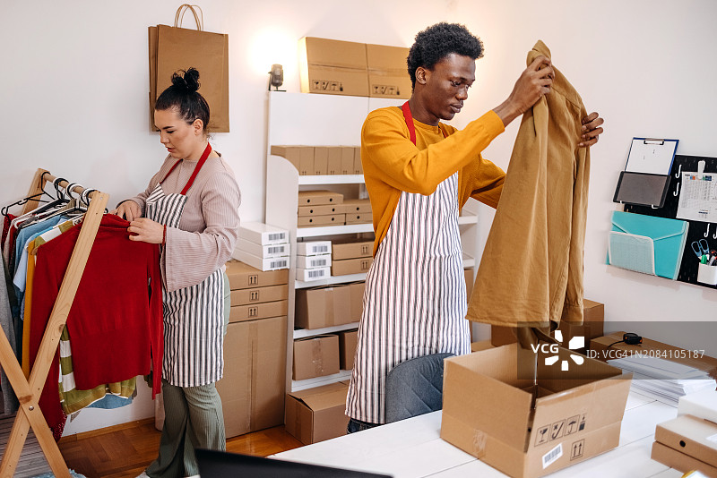 挑选衣服以完成客户订单的年轻人图片素材